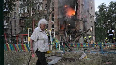 A woman walks past a burning apartment building after a Russian missile attack in Kyiv