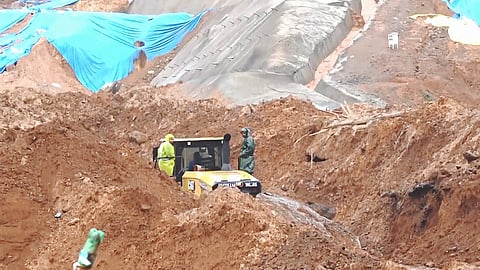 Rescue personnel near an excavator deployed at the site of a massive landslide that struck the under-construction twin tunnel project at Kalladi near Meppadi