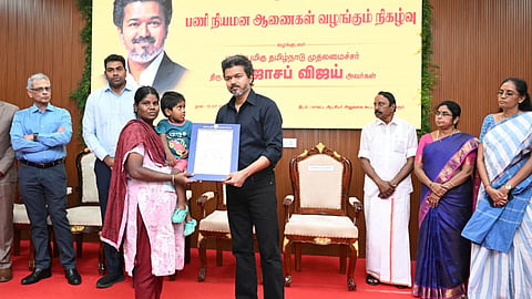 Chief Minister C Joseph Vijay handing over appointment order to a beneficiary at an event in Karur on Friday
