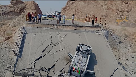 An overturned car sits on a section of a destroyed bridge after a strike in Hormozgan province, southern Iran.