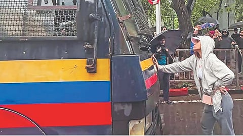 A young woman, later identified as Rhiya, blocks a police vehicle carrying detained protesters, in Mumbai on Wednesday