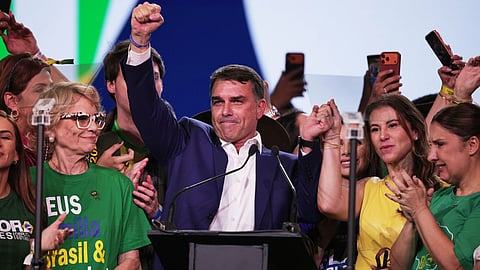 Brazilian Sen. Flavio Bolsonaro, center, and his wife Fernanda raise their arms in unison during the Liberal Party convention where Bolsonaro was confirmed as the party's presidential candidate, in Sao Paulo.