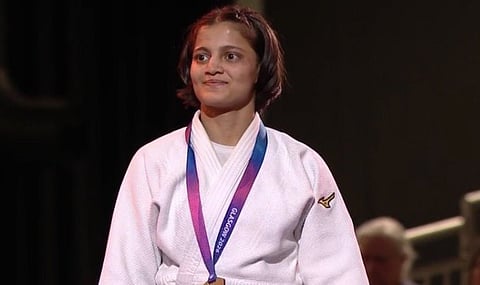 India's Asmita Dey, in white, celebrates after winning a women's 48kg semifinal judo match against Scotland's Summer Shaw