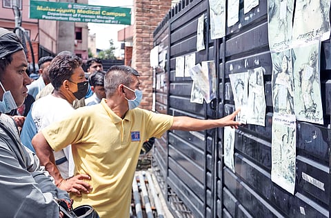 Residents scan posters of recovered and missing people, put up outside Tribhuvan University Teaching Hospital in Kathmandu