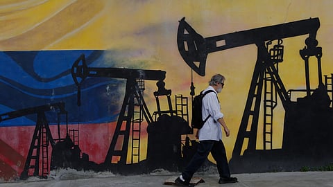 A pedestrian walks past a mural featuring oil wells in Caracas, Venezuela, a day after President Donald Trump announced a deal giving the United States a stake in Venezuela's oil reserves