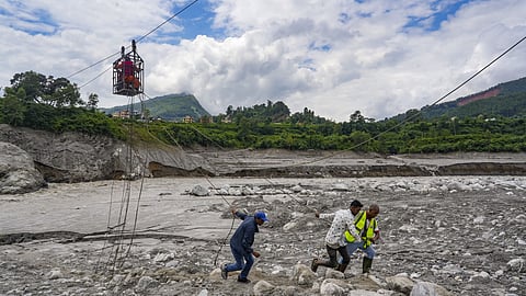Workers pull ropes as people use a makeshift zipline to cross the Trishuli river from Koloni in the aftermath of the recent flash floods, in Nuwakot district, Nepal.