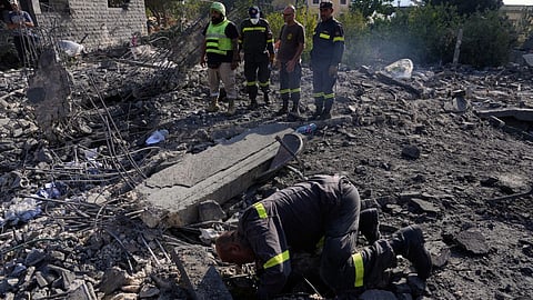 Rescue workers search for victims under the rubble of a building destroyed in an Israeli airstrike in the southern village of Kfar Rumman, Lebanon.