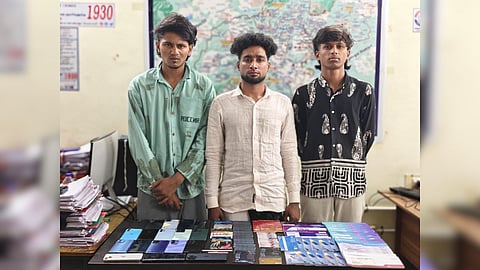 Arrested trio with seized documents and materials.