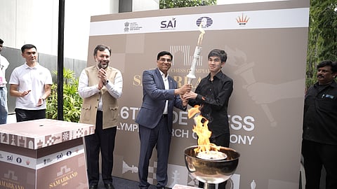 FIDE interim President Viswanathan Anand hands over the ceremonial Olympiad torch to Uzbek GM Javokhir Sindarov, with AICF