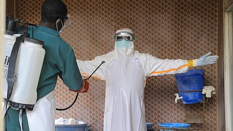 A healthcare worker in protective clothing is disinfected by a collegue.