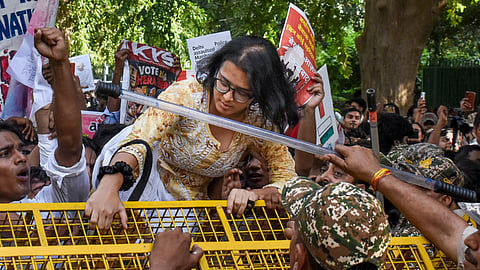 All India Students' Association (AISA) national president Neha Bora climbs a police barricade near Ashoka Road as student activists attempt to march towards Jantar Mantar, demanding the removal of Chief Election Commissioner (CEC) Gyanesh Kumar, in New Delhi, Sunday