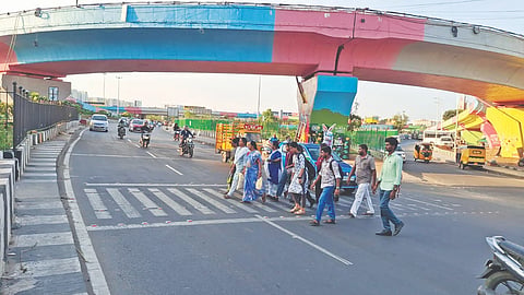 Pedestrians take the risky step to cross the 100 Feet Road in Koyambedu, which also disrupts traffic flow on the stretch