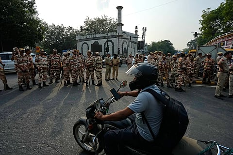 A motorcyclist drives past security personnel