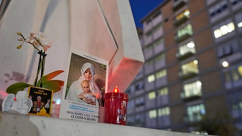 An image of Pope Leo XIV rests at the base of a statue of late pope St. John Paul II outside the Agostino Gemelli Polyclinic, where Leo is hospitalized for surgery to remove a lung nodule, in Rome.