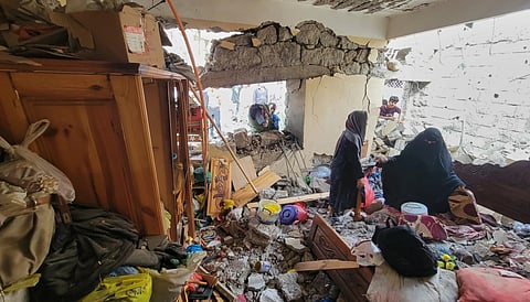 Residents walk on their home debris at Seina district in Taiz, Yemen, after a missile strike