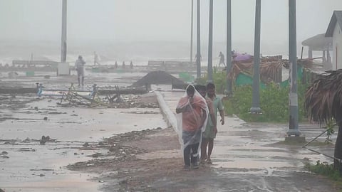 People walk amid strong winds and rainfall at a coastal area during Cyclone Arnab's landfall, in Kakinada, Andhra Pradesh, Wednesday, Oct. 28, 2026