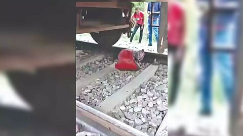 Ruptured gas cylinder being retrieved from railway tracks