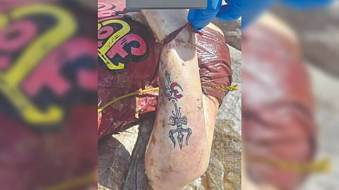 Woman’s forearm tattooed with an Om and trident symbol