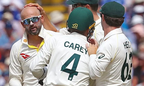 Nathan Lyon (left) celebrates with Australia teammates after picking up the wicket of Joe Root