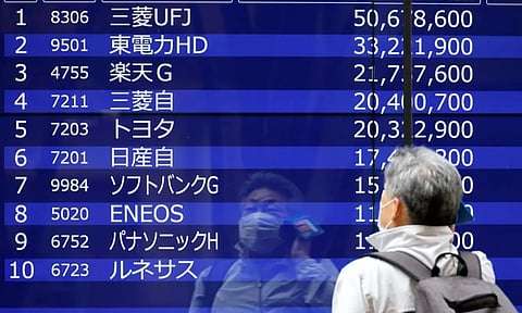A man is reflected on an electric monitor displaying a stock quotation board outside a bank in Tokyo (Photo: REUTERS)