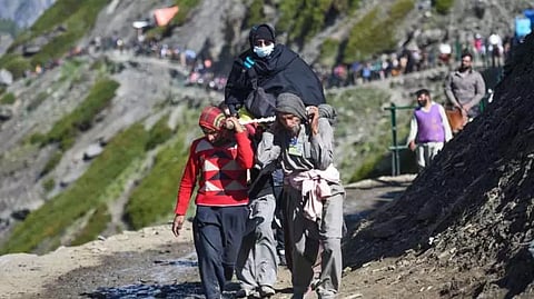 A woman devotee is carried on a palanquin as pilgrims move towards the holy cave shrine of Amarnath