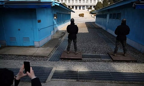 A media member takes a photograph of South Korean soldiers standing guard.