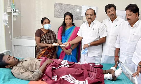 Civil Supplies Minister R Sakkarapani handing over relief to an injured victim at Krishnagiri GH on Sunday