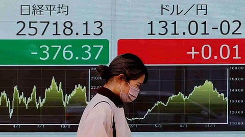 A woman walks past an electric board showing Nikkei index and exchange rate between Japanese Yen and U.S. dollar outside a brokerage at a business district in Tokyo (Photo: Reuters)