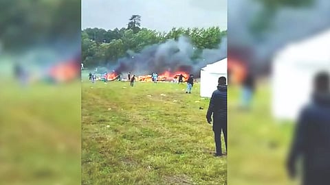 Flames engulfing the sky at an open-air festival with large white tents
