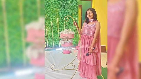 Keshika Manohar standing next to a three-tier wedding cake which she baked