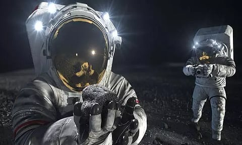 Two suited crew members work on the lunar surface