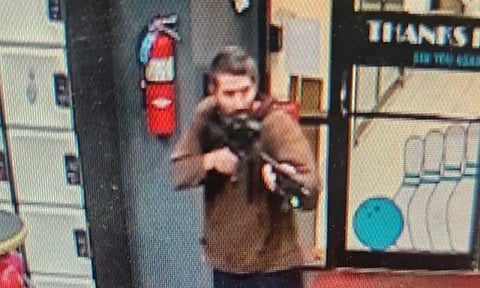 A man identified as a suspect by police points what appears to be a semiautomatic rifle, in Lewiston. (Reuters)