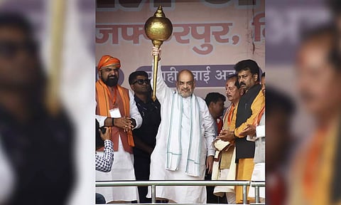 Union Home Minister Amit Shah holds a mace during a public meeting, in Muzaffarpur on Sunday
