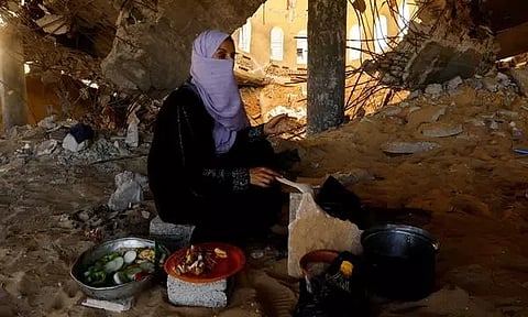 A woman cooks in a destroyed mosque, amid shortages of food supplies and fuel in Khan Younis (Photo: Reuters)