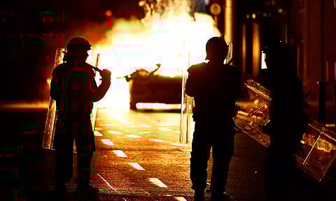 Riot police stands next to a burning police vehicle, near the scene of a suspected stabbing that left few children injured in Dublin, Ireland (Photo: Reuters)