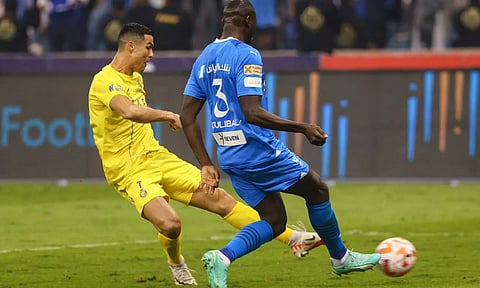 Al-Hilal’s Kalidou Koulibaly challenges Cristiano Ronaldo as he strides to take a shot