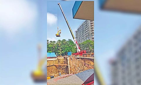 An all-terrain telescopic crane lowering an earthmover into the pit.