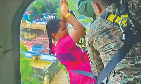 IAF personnel winch up a woman during disaster relief work.