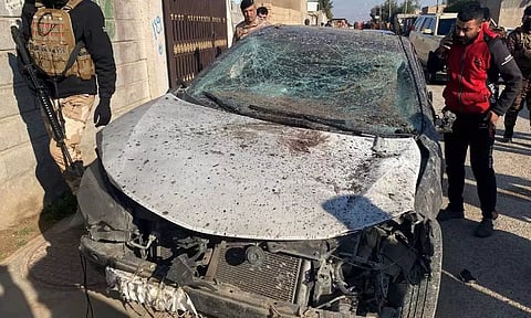 Security forces inspect a damaged car at the site of a US airstrike 