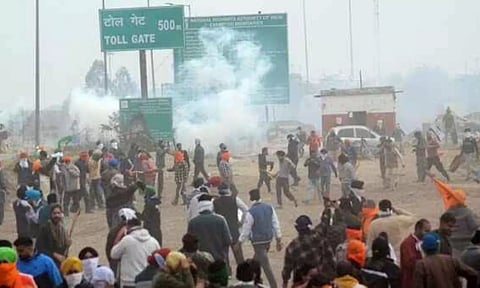 Farmers move away after police fired teargas shell to disperse them during their 'Delhi Chalo' march at Punjab-Haryana Shambhu border near Patiala