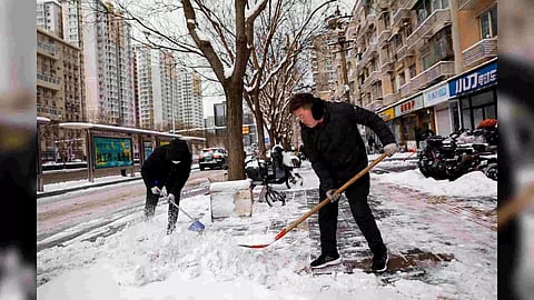 Workers clear snow off a pedestrian road following snowfall in Beijing, China (Photo/Reuters)
