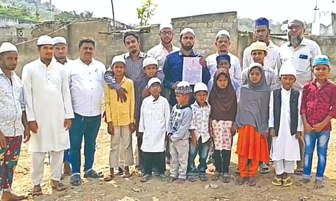 Mohammed Imran poses with registered land document and group of school students