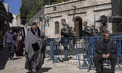 Israeli border police officers stand guard as Palestinians walk by in Jerusalem's Old City on the first day of Ramadan (AP)