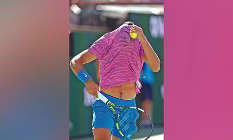 Carlos Alcaraz hides under his shirt as a swarm of bees invade the court