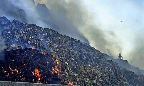 A person picks through trash as a fire rages at Bhalswa landfill (file)