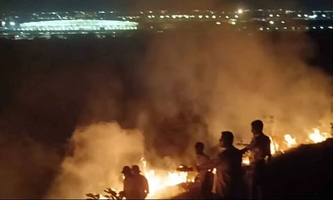 Tamil Nadu Fire and Rescue Service officials dousing the Tirusulam hills fire. Chennai airport can be seen on the top left of the photo