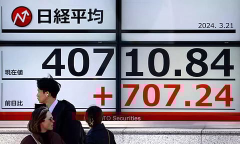 Passersby walk in front of an electric screen displaying Japan's Nikkei share average outside a brokerage in Tokyo (Reuters)