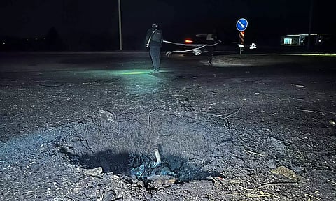Police officers work next to a crater that appeared after a Russian drone strike (Reuters)