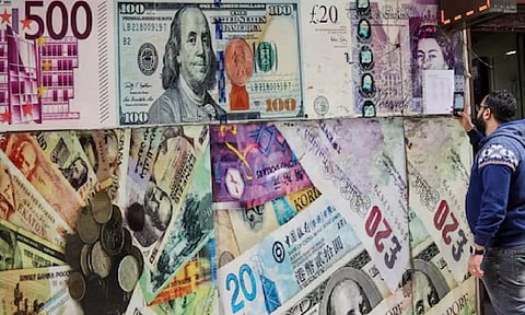 A man takes a photograph of exchange rates in front of an exchange point, displaying images of different currencies, in Cairo (Reuters)