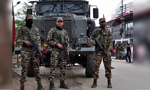 Security personnel stand guard infront of their armoured vehicle 